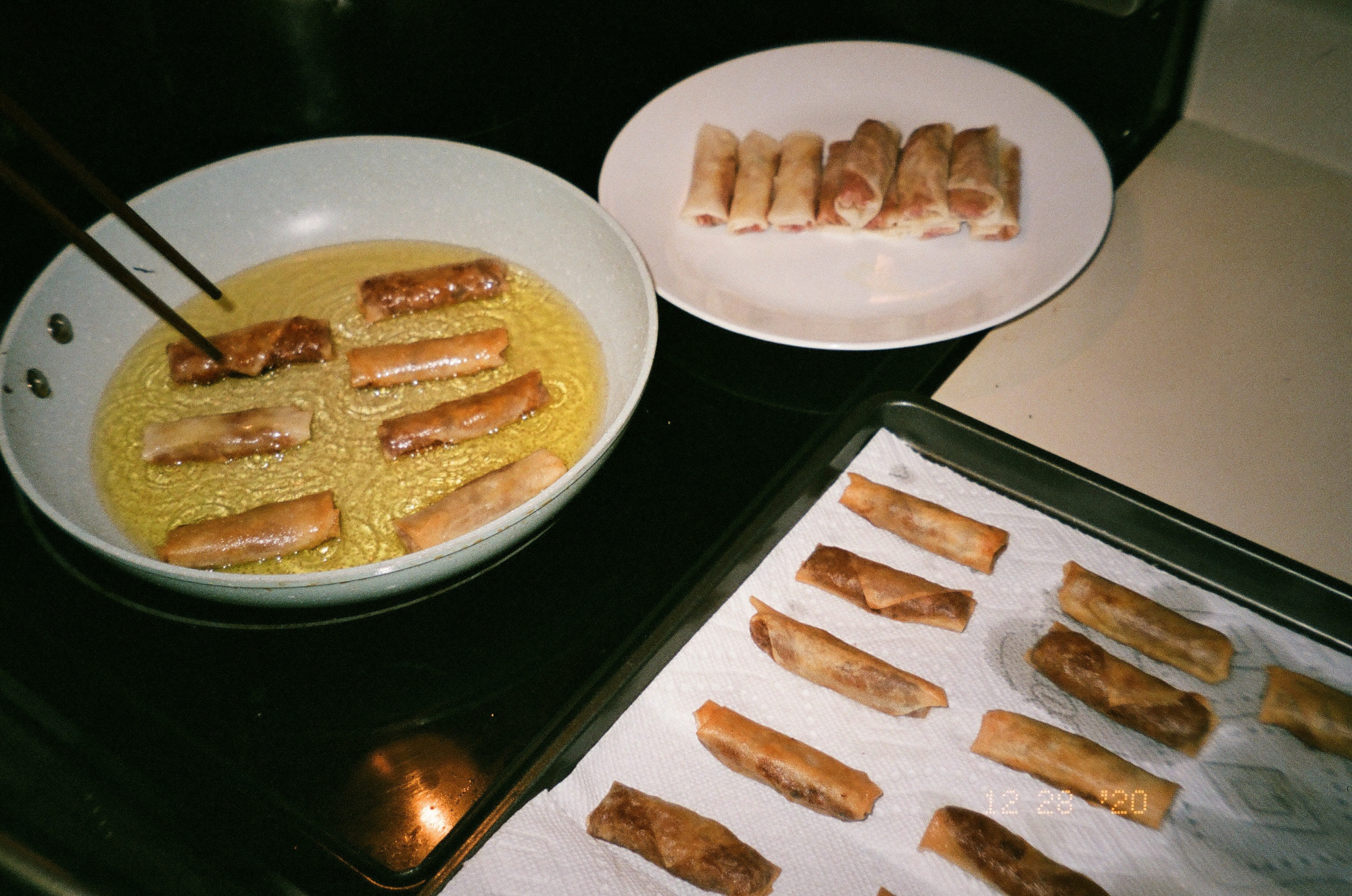 Lumpia in a frying pan and draining on paper towels